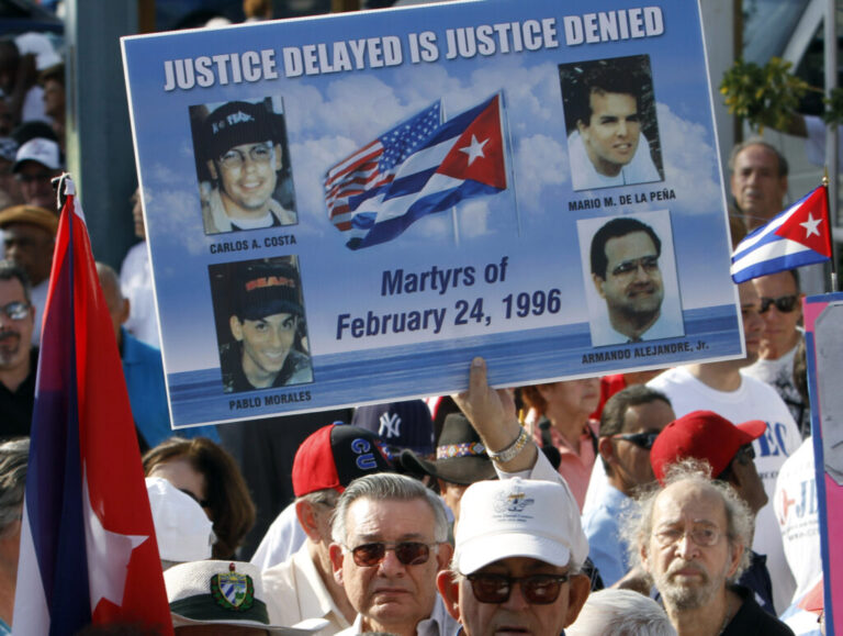 Mario de la Pena carries a poster with the photos of the four pilots shot down by Cuban Migs, his son Mario de la Pena, top right, was among the pilots, during a freedom for Cuba march in Miami, Thursday, Feb. 24, 2011. (AP Photo/Alan Diaz)