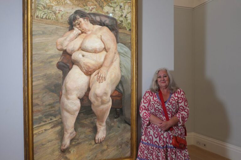 Sue Tilley, a model for British painter Lucian Freud, poses in front of Freud's painting of her, titled