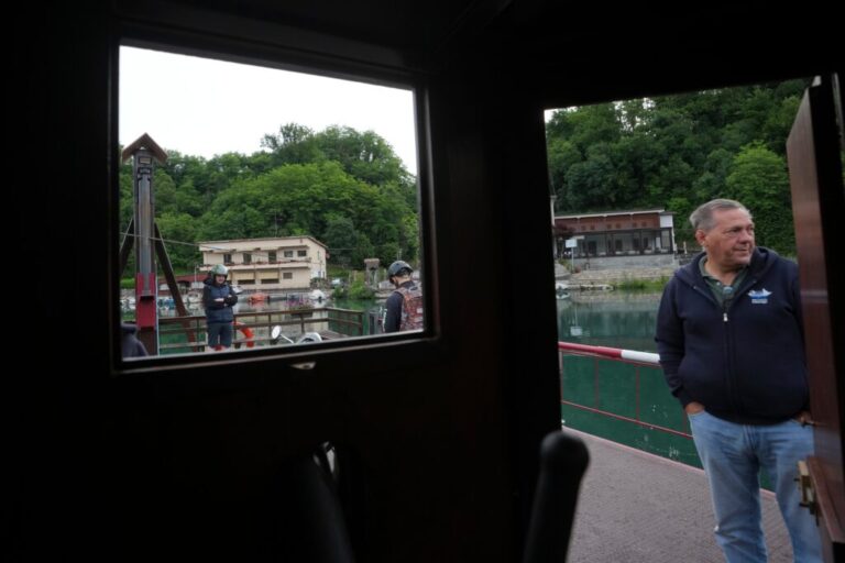 Worker Venanzio Lavelli stands as commuters board the “Da Vinci Ferry,” a hand-operated ferry of a type sketched by Leonardo da Vinci in the 15th century, on the Adda River between the provinces of Lecco and Bergamo, in Imbersago, Italy, Thursday, June 4, 2026. (AP Photo/Luca Bruno)