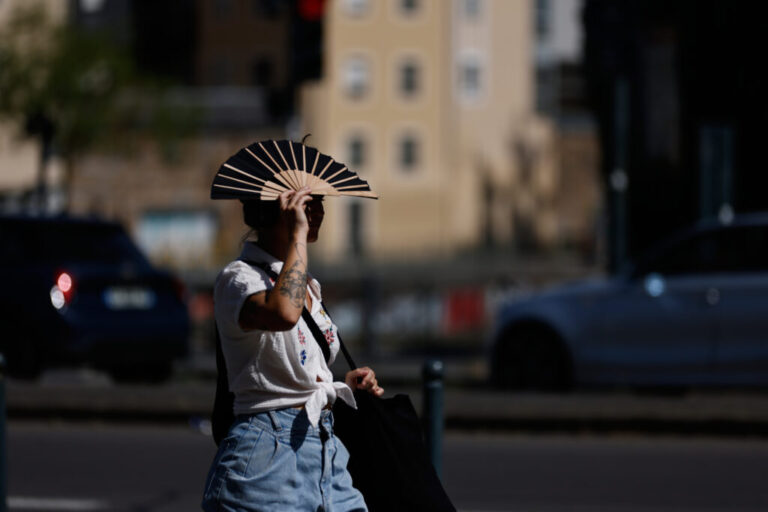 A woman shields herself from the sun with a fan in Rennes, western France, Monday, June 22, 2026. (AP Photo/Jeremias Gonzalez)