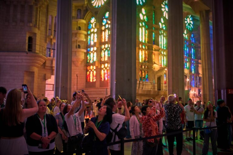 Visitors take photos inside Antoni Gaudí's Basilica of the Sagrada Familia as colored light from its stained-glass windows illuminates the interior in Barcelona, Spain, Tuesday, May 26, 2026, ahead of Pope Leo XIV's visit to the city in June. (AP Photo/Emilio Morenatti)