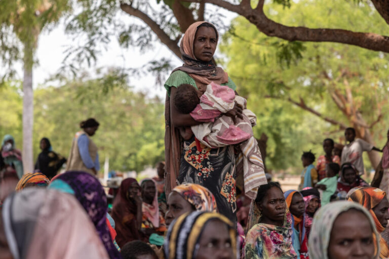 A woman holds her baby outside the registration center for new refugees on the outskirts of the Korsi Refugee Camp in Birao, Central African Republic, Thursday, March 26, 2026. (AP Photo/Caitlin Kelly)
