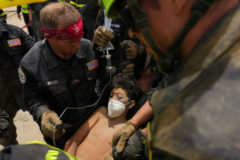 U.S. firefighters from the Fairfax County search and rescue team pull a boy from the rubble after rescuing him and his father from a building that collapsed in the earthquakes in La Guaira, Venezuela, Sunday, June 28, 2026. (AP Photo/Matias Delacroix)