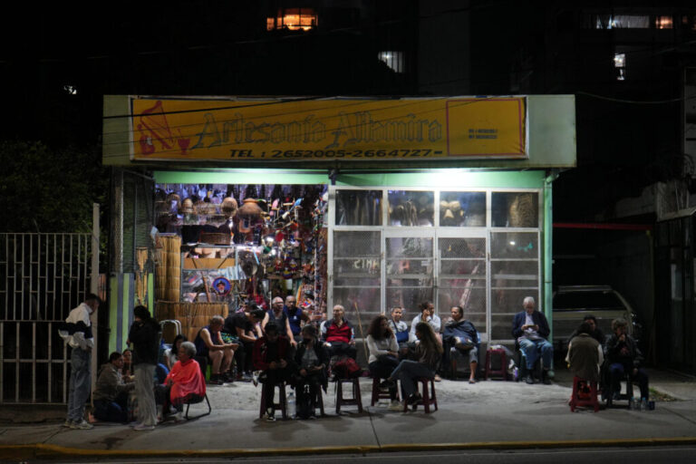 Neighbors gather outside a shop that has power after an earthquake in Caracas, Venezuela, Wednesday, June 24, 2026. (AP Photo/Adrian Naranjo)