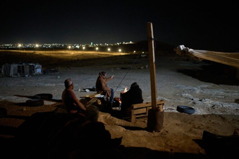 Palestinians sit next to a fire as they take part in a night watch to warn neighbors if Israeli settlers approach their community near the West Bank village of Susya, in the Masafer Yatta region, Thursday, June 18, 2026.. (AP Photo/Leo Correa)