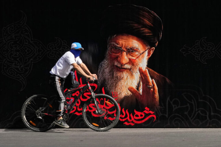 A man rides a bicycle past a portrait of slain Iranian Supreme Leader Ayatollah Ali Khamenei ahead of his dayslong funeral ceremonies in Tehran, Iran, Friday, July 3, 2026. (AP Photo/Vahid Salemi)