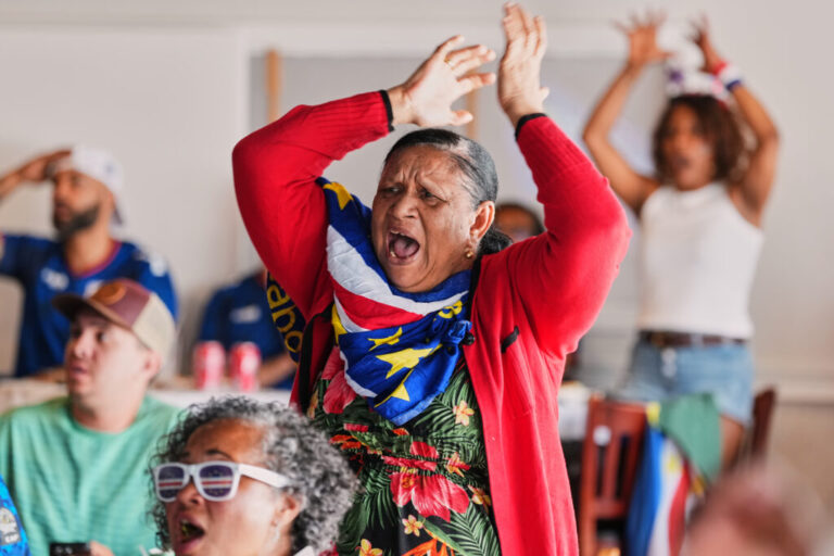 An elderly woman is cheering for Cape Verde during a viewing of the World Cup Group H soccer match between Uruguay and Cape Verde at a restaurant at a Cape Verde community in Brockton, Mass. near Boston, Sunday, June 21, 2026. (AP Photo/Martin Meissner)