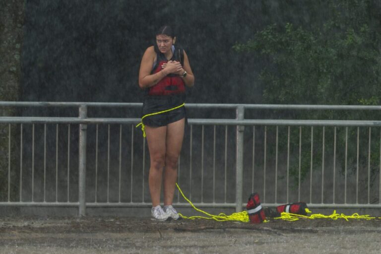 A woman stands on a sidewalk after being rescued from flood waters by members of the Boerne Fire Dept. on Wednesday, July 15, 2026, in Boerne, Texas. (AP Photo/Darren Abate)