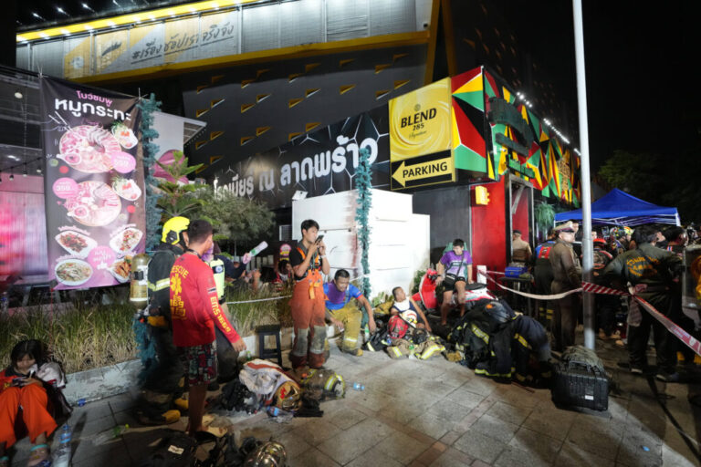 Rescuers rest after putting out a fire in Bangkok, Thailand, Monday, July 13, 2026. (AP Photo/Sakchai Lalit)