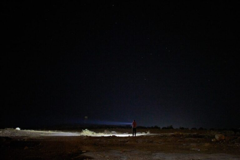 A Palestinian uses a flashlight as he takes part in a night watch to warn neighbors if Israeli settlers approach his community near the West Bank village of Susya, in the Masafer Yatta region, Thursday, June 18, 2026.. (AP Photo/Leo Correa)