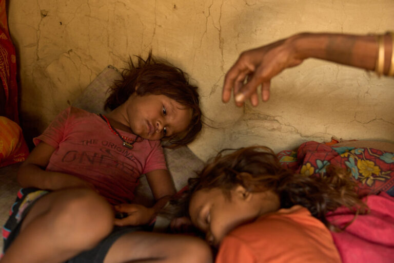 Sonam Mukhiya, left, lies next to her 3-year-old brother, Yubraj Mukhiya, and their grandmother in their home in Gaur, Nepal, on May 19, 2026. Their mother, Kabita Mukhiya, died in December while 28-weeks pregnant amid disruptions to nutrition programs and reproductive outreach services following last year's foreign aid cuts by the United States. (AP Photo/Bram Janssen)