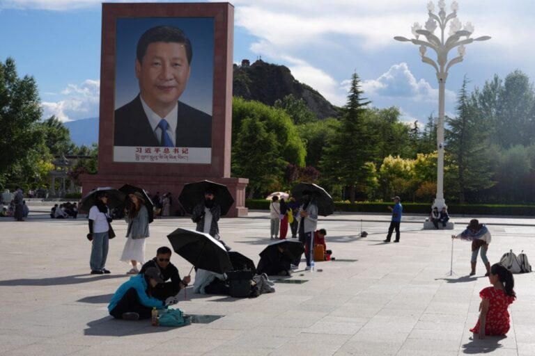 Tourists rest near a portrait of Chinese President Xi Jinping at a public square at the base of the Potala Palace in western China's Tibet autonomous region on July 21, 2026, during a government-organized visit for foreign journalists. (AP Photo/Ng Han Guan)