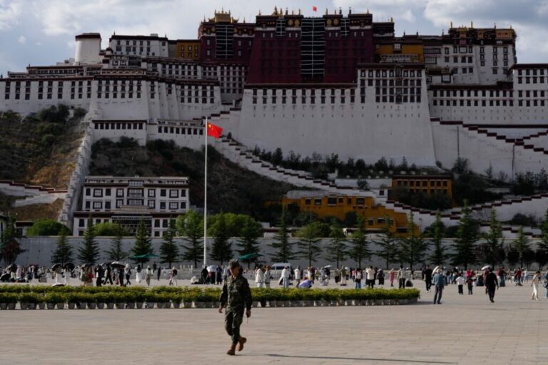 A soldier walks on a public square where a Chinese national flag hangs in front of the Potala Palace in western China's Tibet autonomous region on July 21, 2026, during a government-organized visit for foreign journalists.(AP Photo/Ng Han Guan)