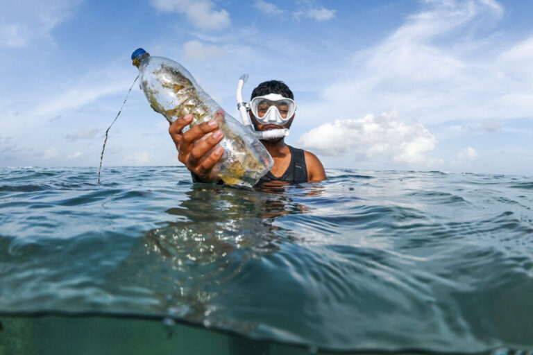 Ahmed Akif Ali, of the youth group Ripple, holds up a plastic bottle found underwater during a clean up session being held with Aloha Ufaa Surf Club, off the coast of Hulhumale, Maldives June 27, 2026. (AP Photo/Sophia Nasif)