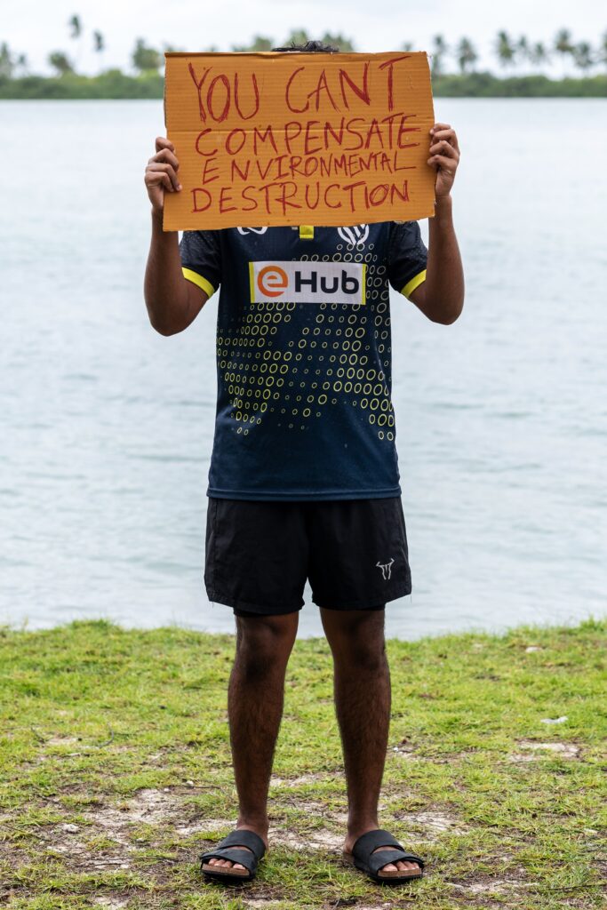 A demonstrator holds a sign while participating in an action as part of Project ThimaaVeshi, a youth-led protest against ongoing reclamation projects damaging mangroves, in Addu City, Maldives, June 3, 2026. (AP Photo/Sophia Nasif)