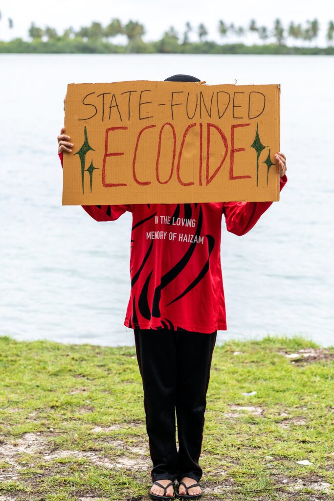 A demonstrator holds a sign while participating in an action as part of Project ThimaaVeshi, a youth-led protest against ongoing reclamation projects damaging mangroves, in Addu City, Maldives, June 3, 2026. (AP Photo/Sophia Nasif)