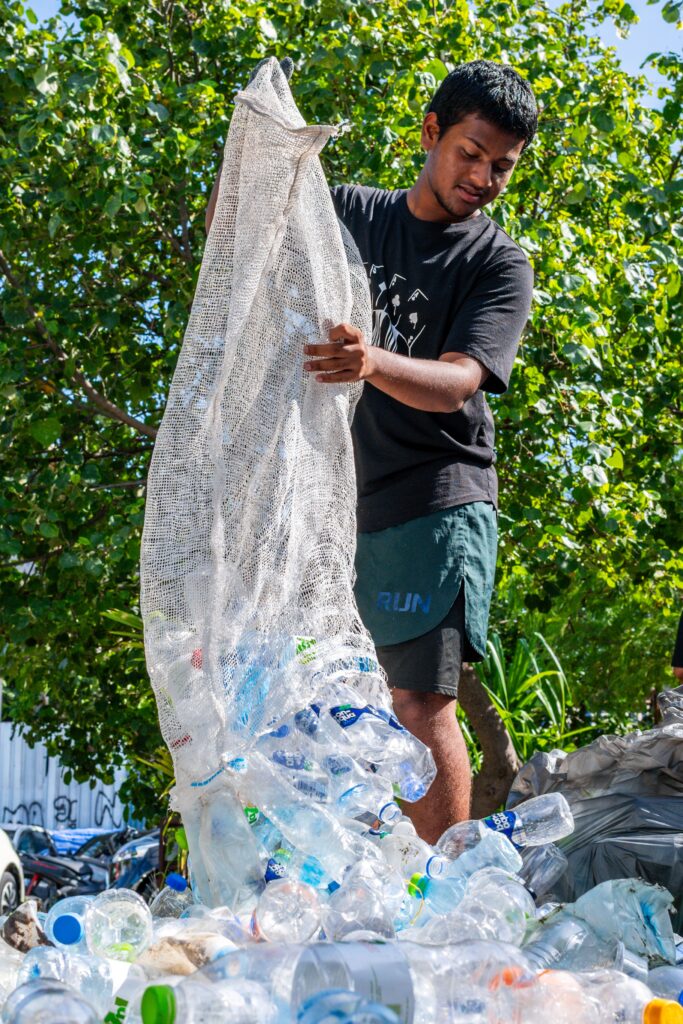Mohamed Ma'al Nazeel, co-founder of Ripple, a youth led group, empties out his full bag of plastic waste collected during a joint plastic pollution clean-up in Male, Maldives, June 19, 2026. (AP Photo/Sophia Nasif)